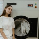 Kobieta w pralni przy pralce zastanawia się, jak ją wyczyścić