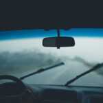 Widok z wnętrza auta na deszczu, krople na szybie, działające wycieraczki